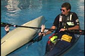 rescuer grabs wrist of paddler and places it on bridging paddle shaft